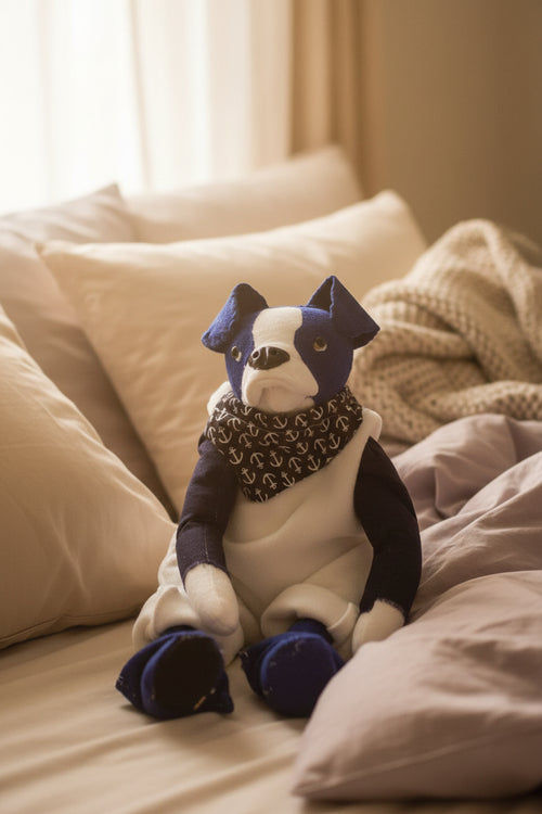 Stuffed dog toy with a purple bow tie and sweater on a beige background