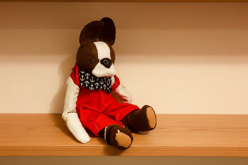 Stuffed animal toy resembling a dog in a red outfit with a white background
